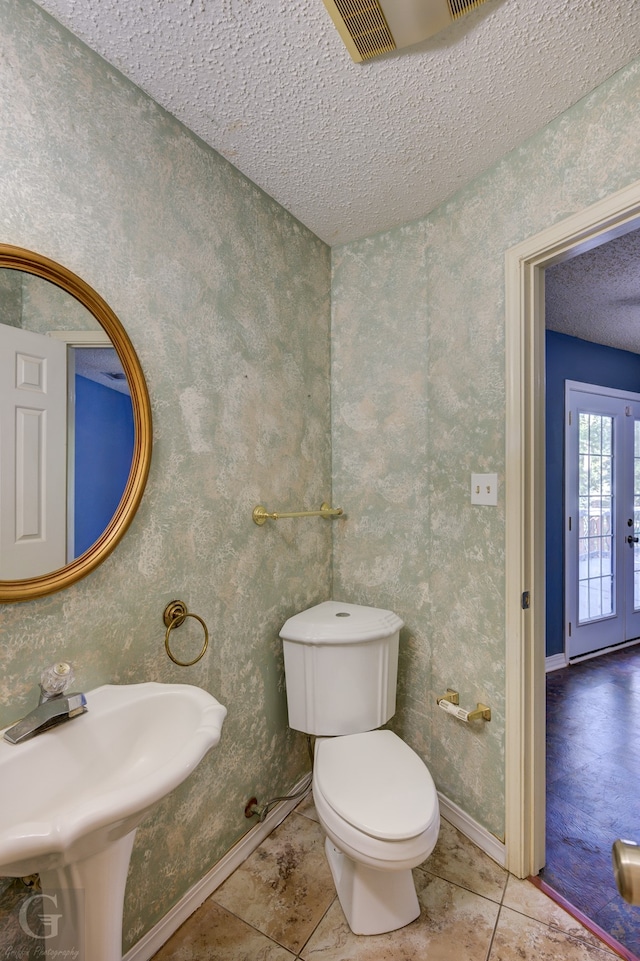 bathroom featuring a textured ceiling, tiled shower / bath combo, and toilet