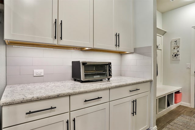 kitchen featuring light stone countertops, dark hardwood / wood-style floors, backsplash, and white cabinets