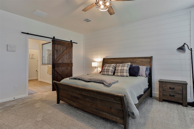 bedroom with a barn door, light colored carpet, and ceiling fan