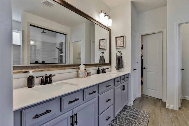 bathroom with vanity, hardwood / wood-style flooring, and tiled shower