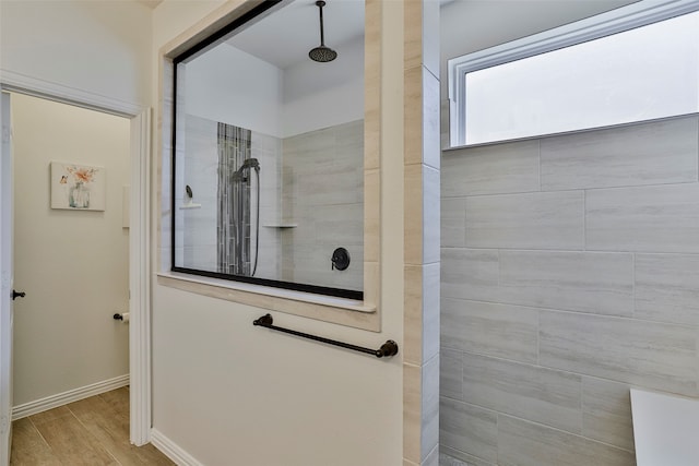 bathroom with wood-type flooring and tiled shower