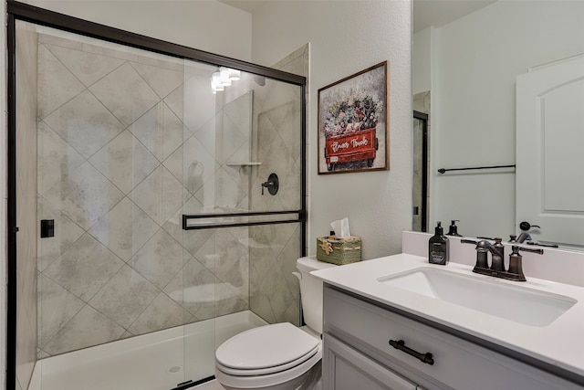 bathroom with vanity, a shower with shower door, and toilet