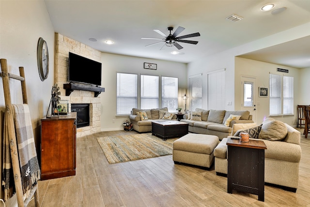 living room with ceiling fan, light wood-type flooring, and a fireplace