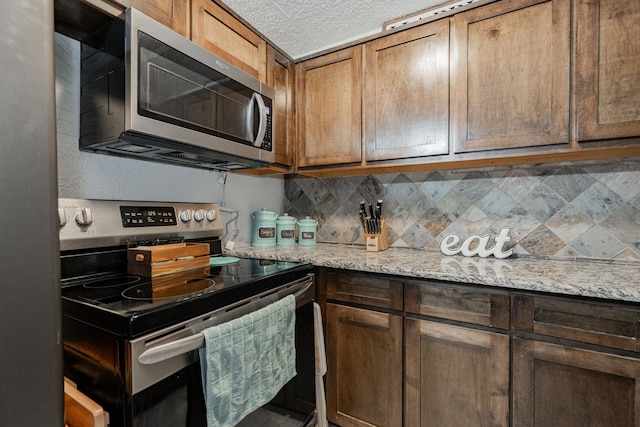 kitchen with light stone countertops, stainless steel appliances, and tasteful backsplash