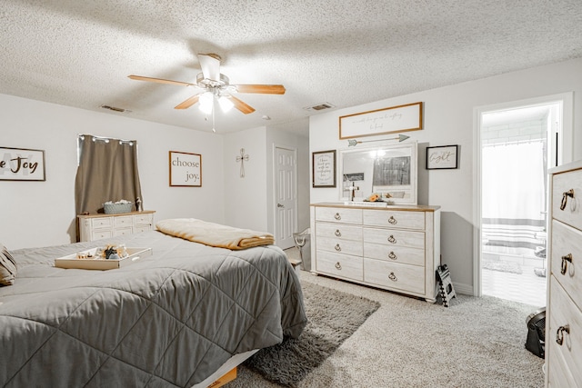 carpeted bedroom with a textured ceiling, ensuite bathroom, and ceiling fan