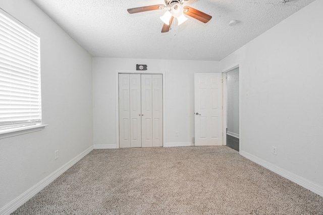 unfurnished bedroom featuring carpet, a textured ceiling, a closet, and ceiling fan