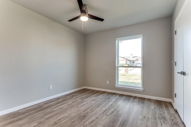 spare room featuring light wood-style flooring, baseboards, and ceiling fan