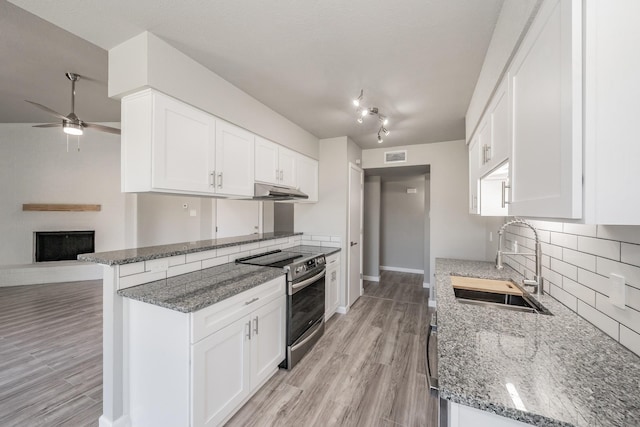 kitchen with kitchen peninsula, sink, stainless steel range with electric cooktop, stone counters, and white cabinetry