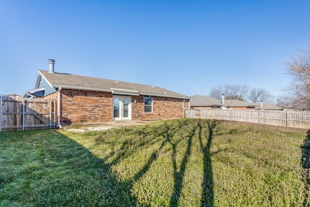 back of property with brick siding, a lawn, and a fenced backyard