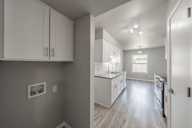 kitchen with appliances with stainless steel finishes, white cabinetry, sink, and light hardwood / wood-style floors