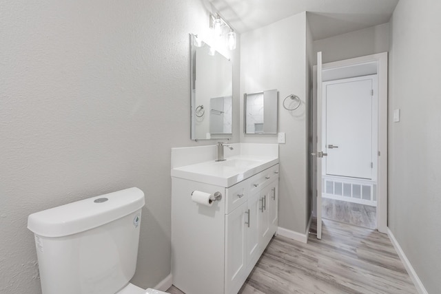 bathroom with toilet, hardwood / wood-style flooring, and vanity