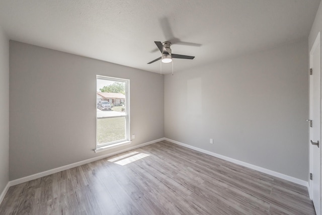 unfurnished room with a textured ceiling, light wood-type flooring, and ceiling fan