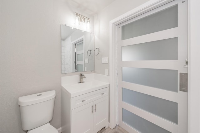 bathroom featuring toilet, hardwood / wood-style flooring, and vanity