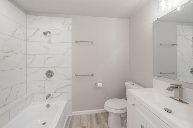 full bathroom featuring toilet, tiled shower / bath, hardwood / wood-style floors, and vanity