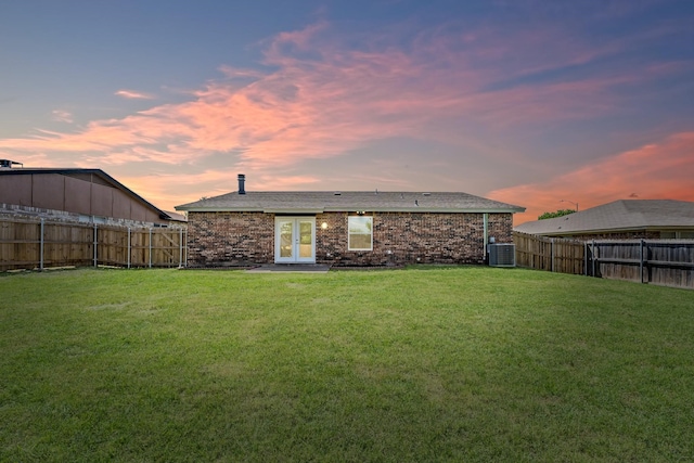 back house at dusk with a lawn and cooling unit