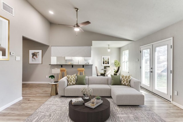 living room with lofted ceiling, french doors, wood finished floors, and visible vents