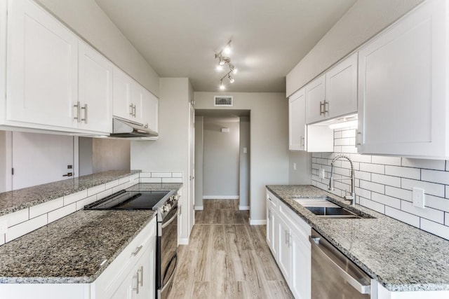 kitchen featuring under cabinet range hood, a sink, visible vents, appliances with stainless steel finishes, and tasteful backsplash