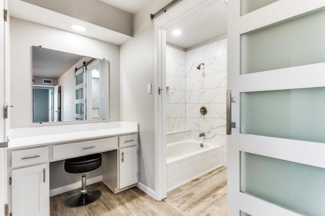 bathroom with shower / tub combination, visible vents, wood finished floors, and vanity