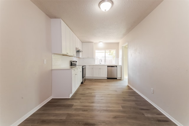 kitchen with dark wood-type flooring, tasteful backsplash, appliances with stainless steel finishes, and white cabinets