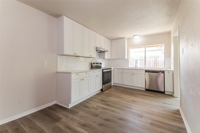 kitchen featuring hardwood / wood-style flooring, stainless steel appliances, sink, white cabinets, and a textured ceiling