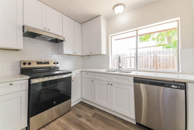 kitchen with appliances with stainless steel finishes, white cabinets, hardwood / wood-style flooring, and sink