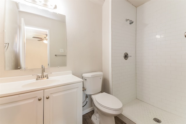 bathroom featuring a tile shower, toilet, ceiling fan, vanity, and hardwood / wood-style flooring