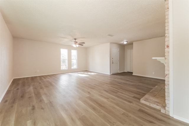 unfurnished living room featuring ceiling fan, a textured ceiling, a brick fireplace, and hardwood / wood-style floors