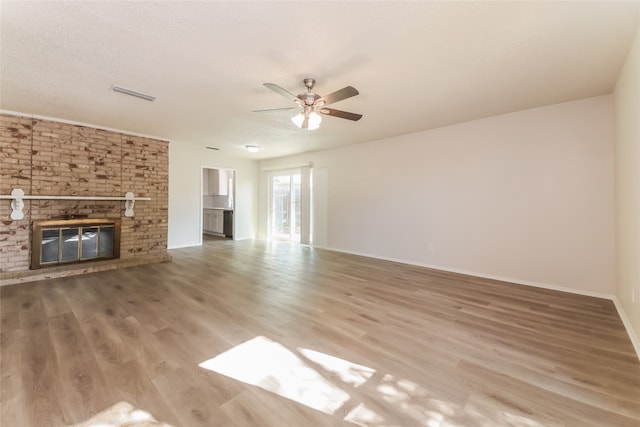 unfurnished living room with a textured ceiling, a brick fireplace, hardwood / wood-style flooring, and ceiling fan