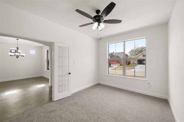 carpeted spare room featuring french doors and ceiling fan with notable chandelier