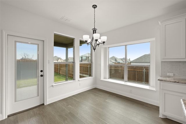 unfurnished dining area with a chandelier and dark wood-type flooring