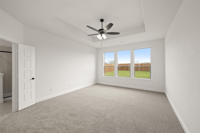 spare room featuring ceiling fan, light carpet, and a tray ceiling