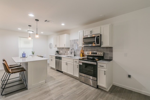 kitchen with white cabinetry, stainless steel appliances, pendant lighting, and a kitchen island