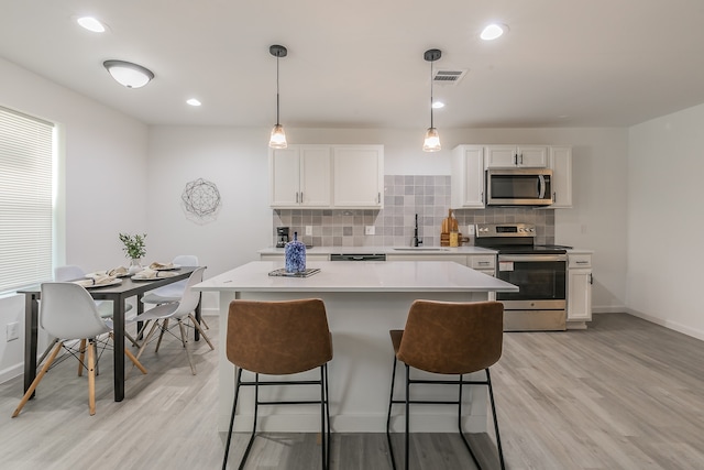 kitchen with white cabinetry, light hardwood / wood-style flooring, appliances with stainless steel finishes, and sink