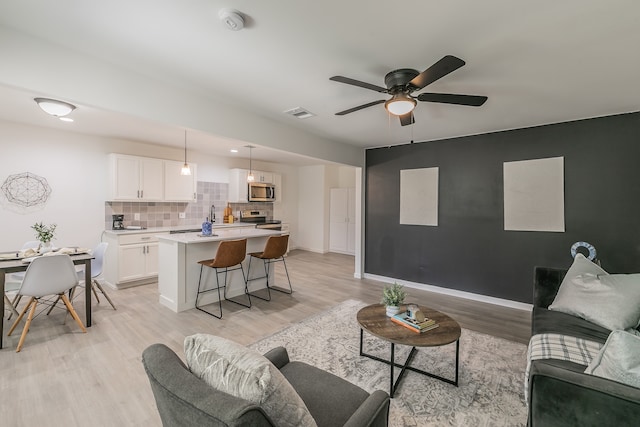 living room with sink, light wood-type flooring, and ceiling fan