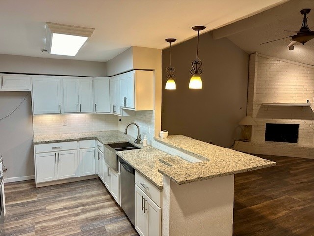 kitchen featuring hanging light fixtures, kitchen peninsula, sink, vaulted ceiling, and white cabinets