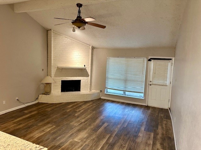 unfurnished living room featuring ceiling fan, dark hardwood / wood-style flooring, a textured ceiling, vaulted ceiling with beams, and a fireplace