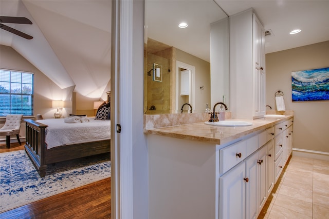 bathroom with wood-type flooring, vaulted ceiling, walk in shower, vanity, and ceiling fan