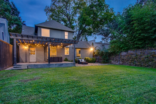 back house at dusk with a pergola, a patio area, and a yard