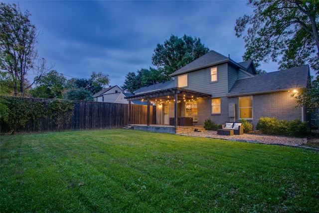 back house at dusk featuring a patio area, central AC, and a lawn