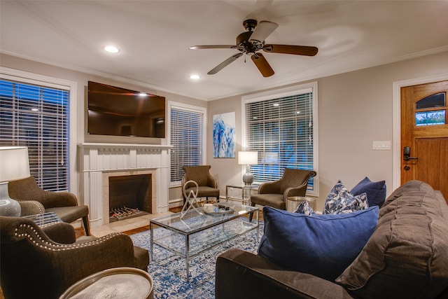 living room with crown molding, a tile fireplace, and ceiling fan