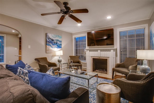 living room with tile patterned flooring, crown molding, a tile fireplace, and ceiling fan