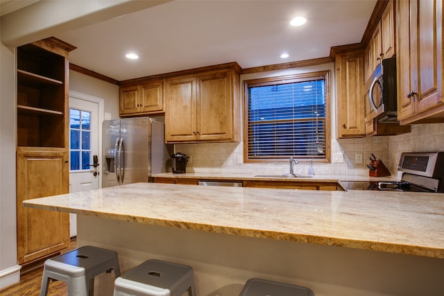 kitchen featuring light stone counters, stainless steel appliances, sink, and a kitchen breakfast bar