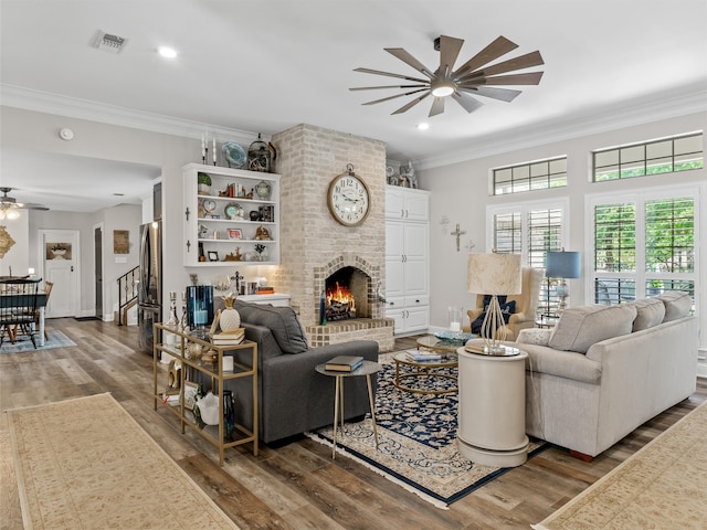 living room featuring ceiling fan, crown molding, a fireplace, and hardwood / wood-style floors