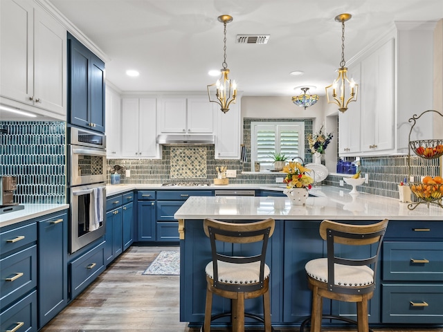 kitchen featuring a kitchen bar, decorative light fixtures, white cabinetry, appliances with stainless steel finishes, and light hardwood / wood-style floors