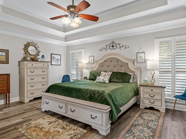 bedroom featuring crown molding, a raised ceiling, dark hardwood / wood-style flooring, and ceiling fan