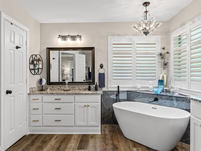 bathroom with vanity, hardwood / wood-style floors, a chandelier, and a washtub