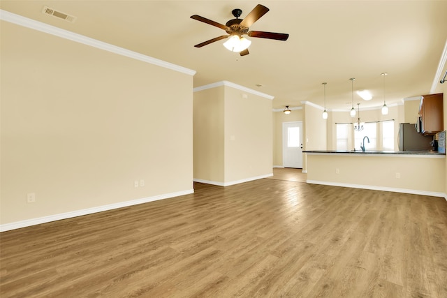 unfurnished living room with ornamental molding, sink, light wood-type flooring, and ceiling fan