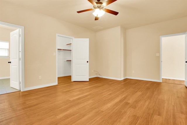 unfurnished bedroom featuring a closet, light hardwood / wood-style flooring, a spacious closet, and ceiling fan