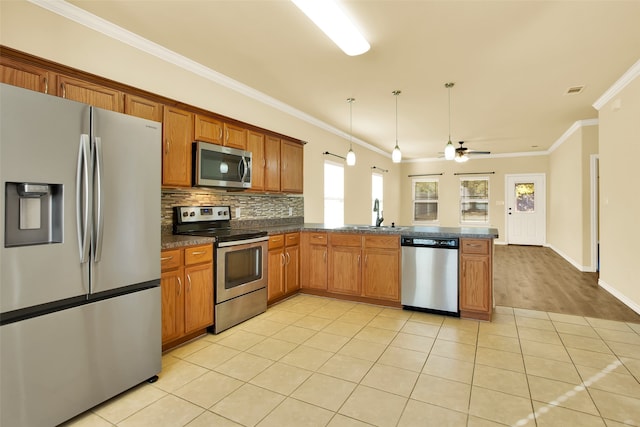 kitchen featuring kitchen peninsula, hanging light fixtures, stainless steel appliances, ornamental molding, and light hardwood / wood-style flooring