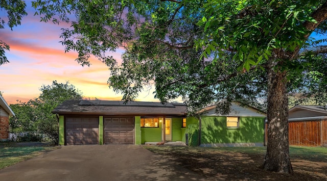 ranch-style house featuring solar panels, a yard, and a garage